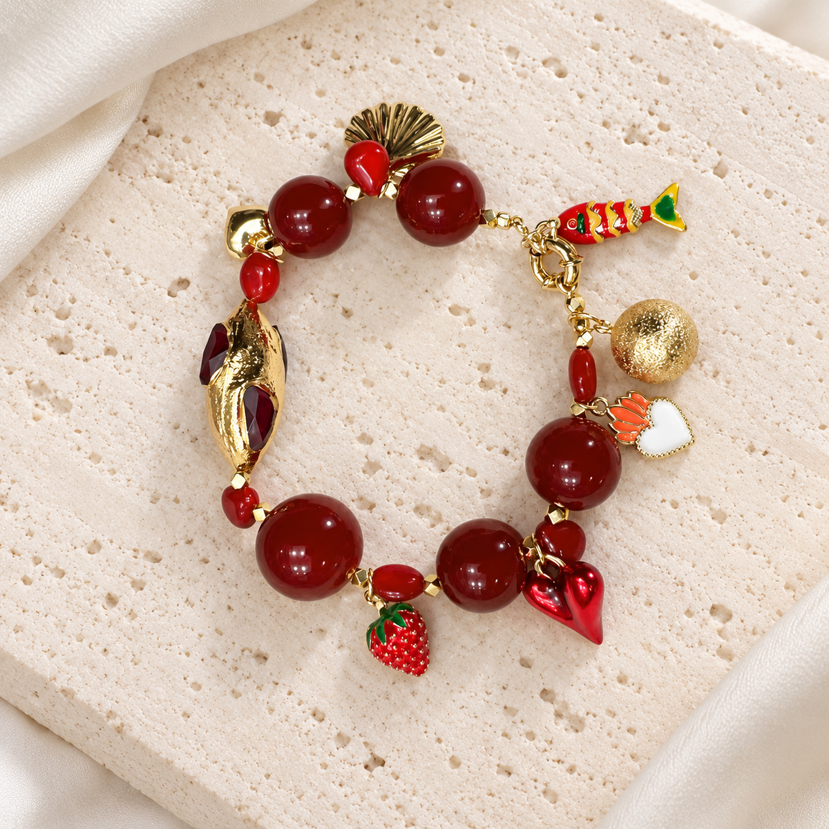 Scarlet Agate Heart Charm Bracelet — full bracelet on a cream stone surface