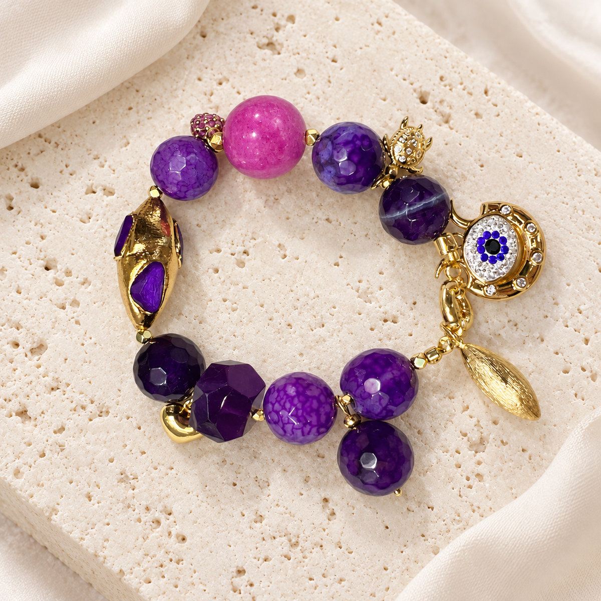 Violet Agate Eye Charm Bracelet — full bracelet on a cream stone surface