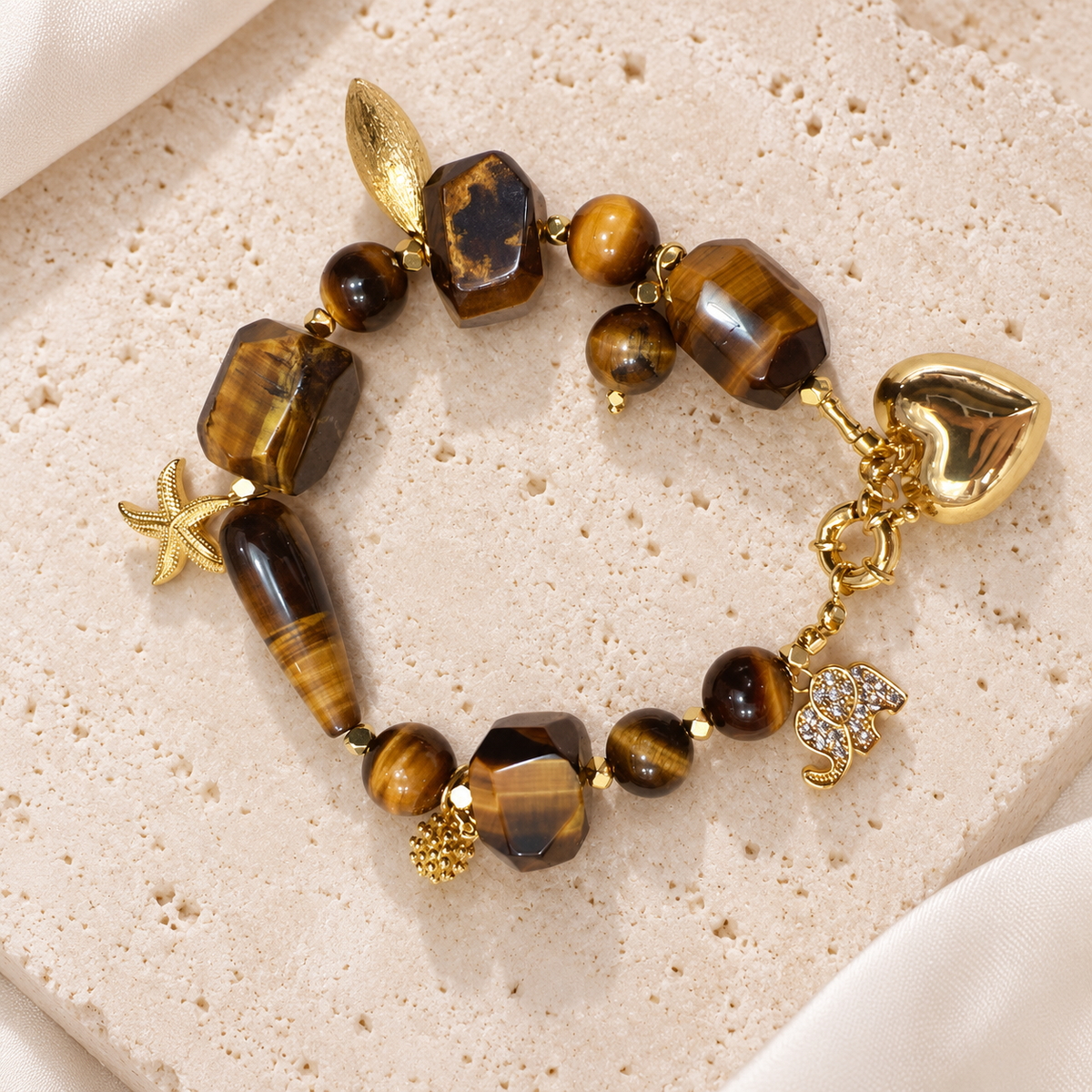 Golden Tiger Eye Charm Bracelet — full bracelet on a cream stone surface